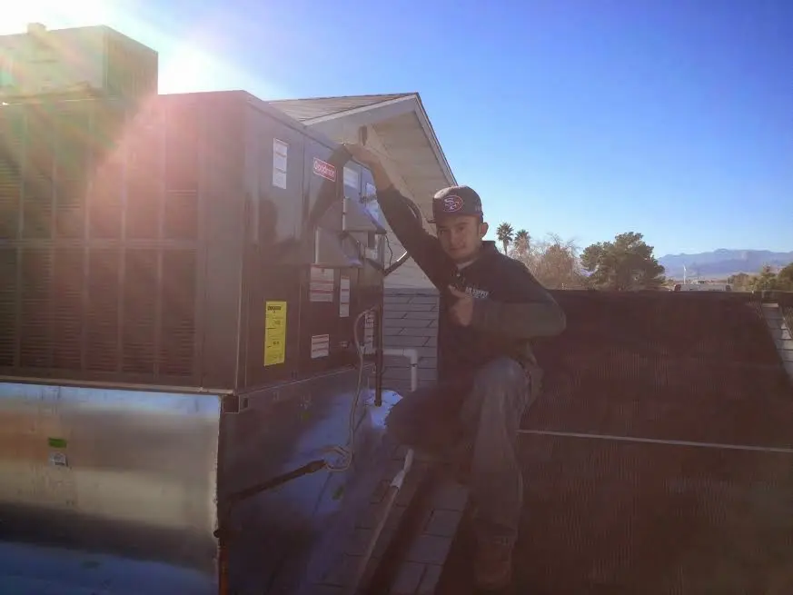 HVAC technician performing AC Tune-Up on a rooftop unit in Olympia Heights