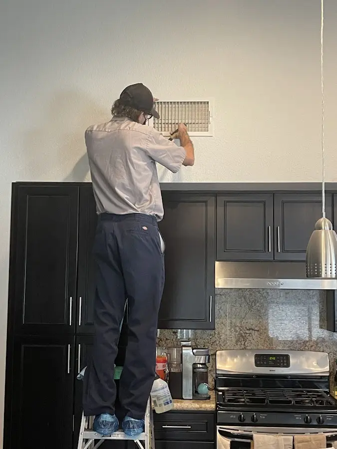 Technician inspecting an air vent during HVAC service in Olympia Heights